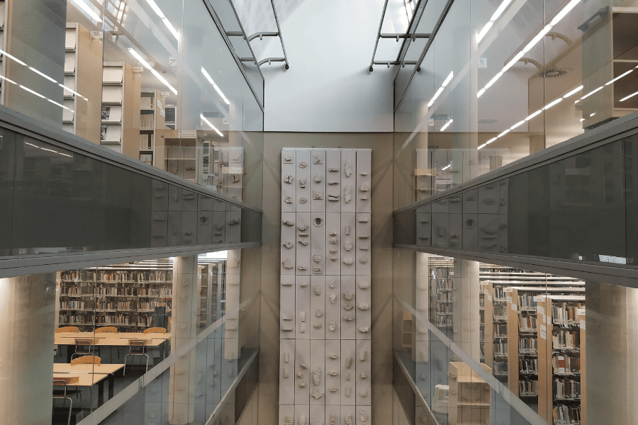 Interior of the communication library with shelves full of books and a visible wall in the background.